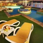 A luxury twin-bed cabin on a cruise ship with a large window looking out onto the Nile River.