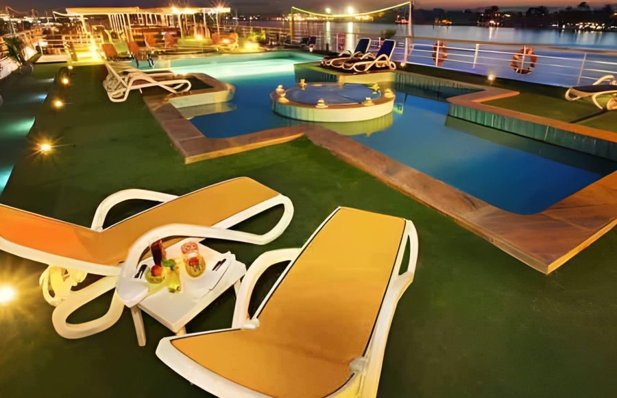 A luxury twin-bed cabin on a cruise ship with a large window looking out onto the Nile River.