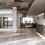 Modern cruise ship bar and lounge area with wood paneling, open shelves, and multi-colored velvet seating.