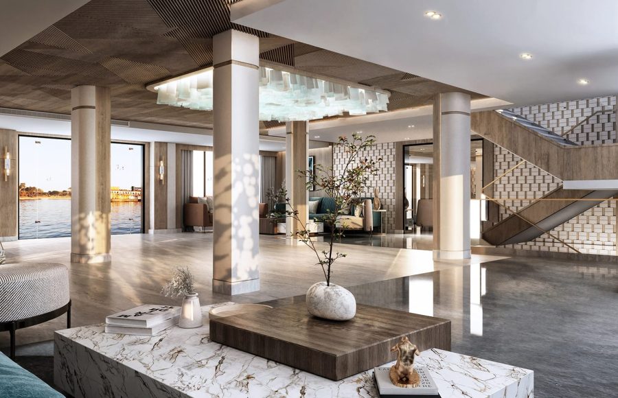 Modern cruise reception desk made of white marble with "Liberty Story Cruise" lettering and two green velvet ottomans.