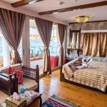 A spacious boat cabin with a double bed, swan-shaped towels, and floor-to-ceiling windows.