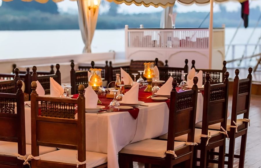 A formal dinner table set with white cloths, candles, and wine glasses at twilight.