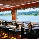 Shaded sundeck with dark wood sofas, decorative cushions, and views of the riverbank.