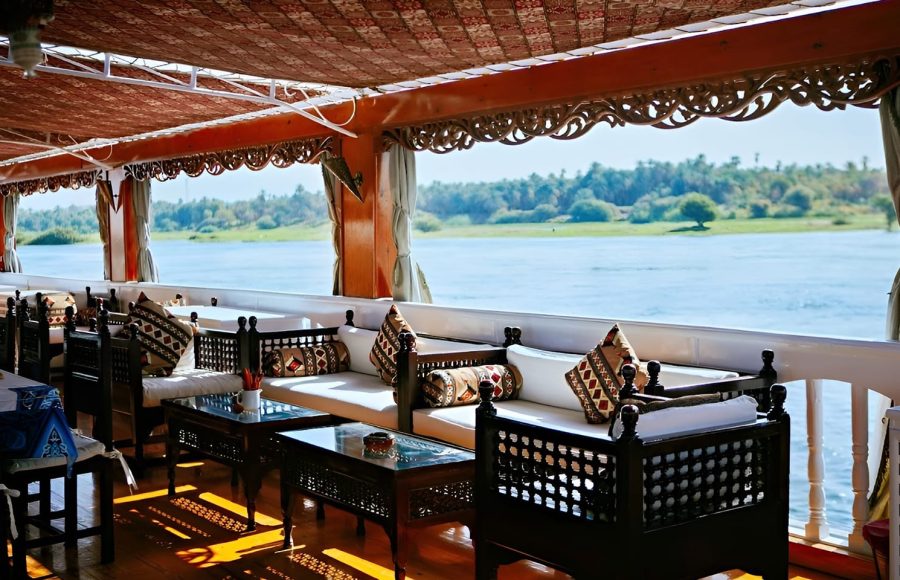 Shaded sundeck with dark wood sofas, decorative cushions, and views of the riverbank.