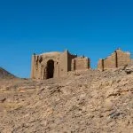 The sun-baked mud-brick ruins of An Ancient Christian Bagawat Cemetery One Of The Oldest In The World Kharga Oasis Egypt, set against a clear blue sky in the Western Desert.
