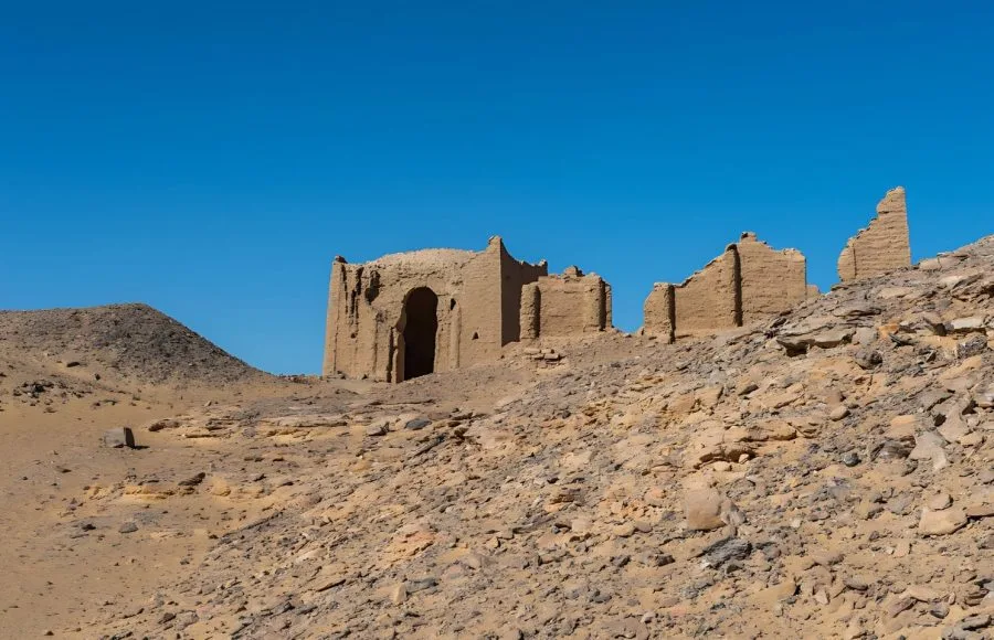 The sun-baked mud-brick ruins of An Ancient Christian Bagawat Cemetery One Of The Oldest In The World Kharga Oasis Egypt, set against a clear blue sky in the Western Desert.
