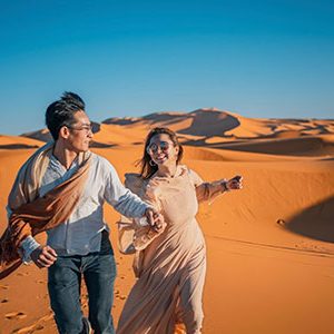 Asian Chinese Couple running in Morocco Sahara Desert during their 11 day Egypt Morocco and Sahara tour