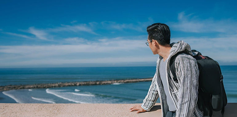 Asian Chinese male tourist looking at North Atlantic Ocean Rabat beach viewing from Kasbah of the Udayas