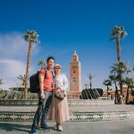 Asian-Chinese-tourist-couple-looking-at-camera-in-front-of-fountain-Koutoubia-Mosque-Morocco