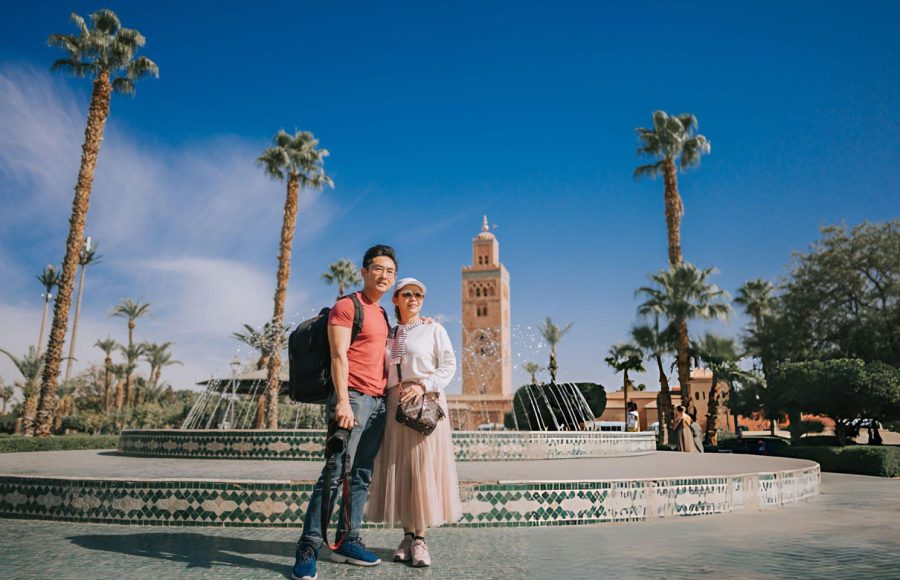 Asian-Chinese-tourist-couple-looking-at-camera-in-front-of-fountain-Koutoubia-Mosque-Morocco