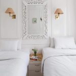 A bright, white twin-bed cabin on a Dahabiya Nile cruise boat with ornate wall molding and a decorative mirror.