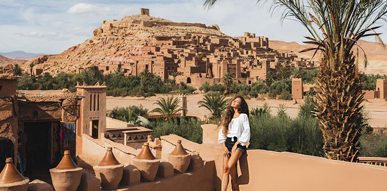 Beautiful young woman happy to travel in Morocco Ait Ben Haddou kasbah on background