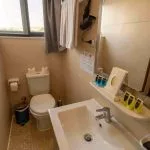 A modern, clean bathroom on a Nile cruise ship with a white sink, toilet, and travel-sized toiletries.