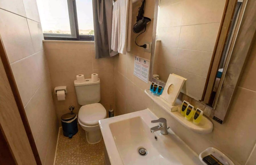 A modern, clean bathroom on a Nile cruise ship with a white sink, toilet, and travel-sized toiletries.