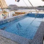 A small, tiled rectangular swimming pool on the deck of a boat overlooking the river.
