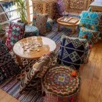 A cozy lounge area on a boat deck with patterned floor cushions, low wooden tables, and board games.