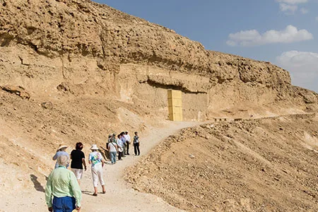 Tourists walk along a desert path leading to the tombs of Beni Hassan on a Beni Hassan tour in Middle Egypt