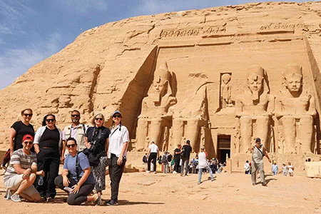 A group of happy tourists posing in front of the impressive Abu Simbel temple from Cairo day trip