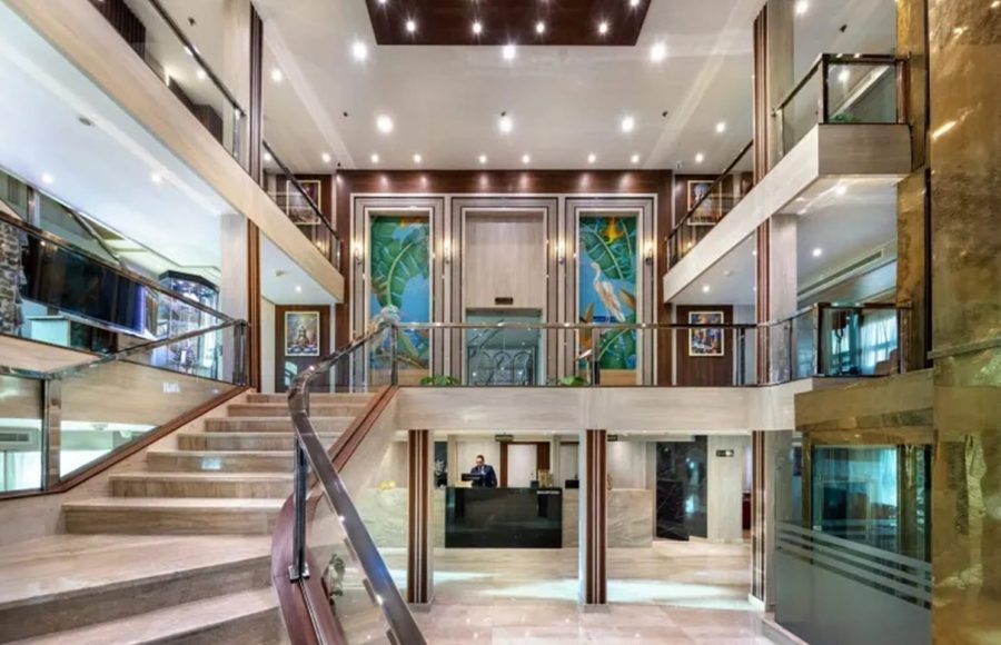 Multi-level cruise ship reception area with staircase and lift.