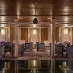 Cruise ship lounge with comfortable seating and wooden paneling.