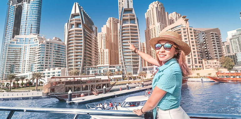 Cheerful Girl Traveler On A Ferry Boat Sailing Through Dubai Marina Port Among Huge Skyscrapers