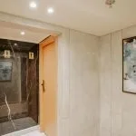 A contemporary hallway entrance to a public restroom area on a Nile Cruise, featuring light marble-look walls, a wooden door, and a black marble-look entrance with restroom icons.