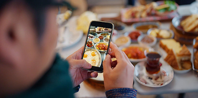 Close up of man solo traveler tourist taking photos and videos of Turkish breakfast in cafe in Istanbul
