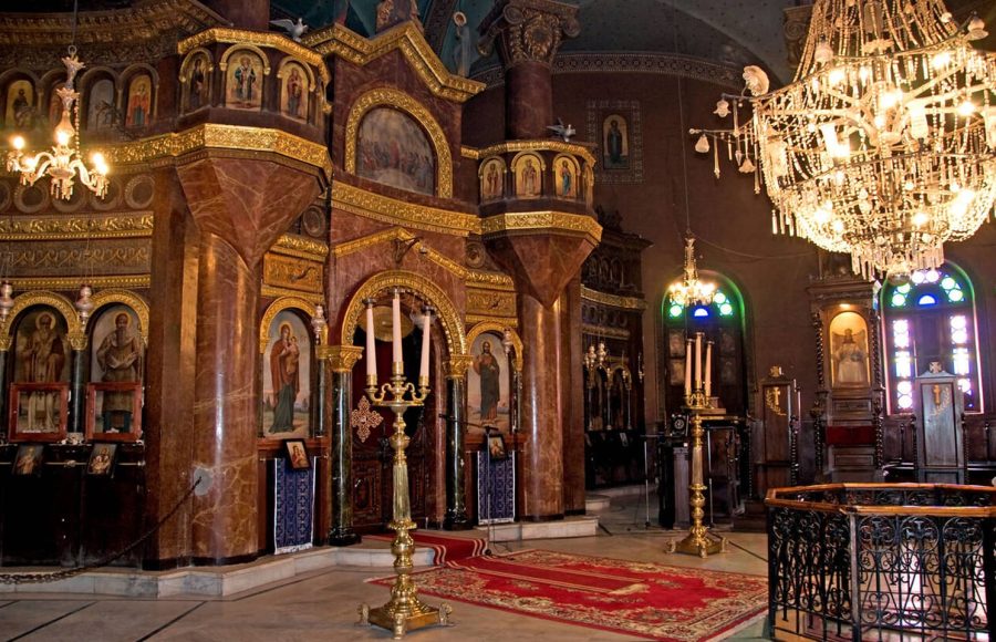 Ornate interior sanctuary of a church in Coptic Old Cairo, featuring icons and a large chandelier.