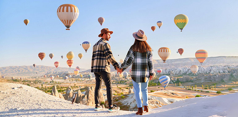 Couple travelers vacations together in beautiful destination in Goreme Turkey Fabulous Kapadokya with flying air balloons at sunrise Anatolia