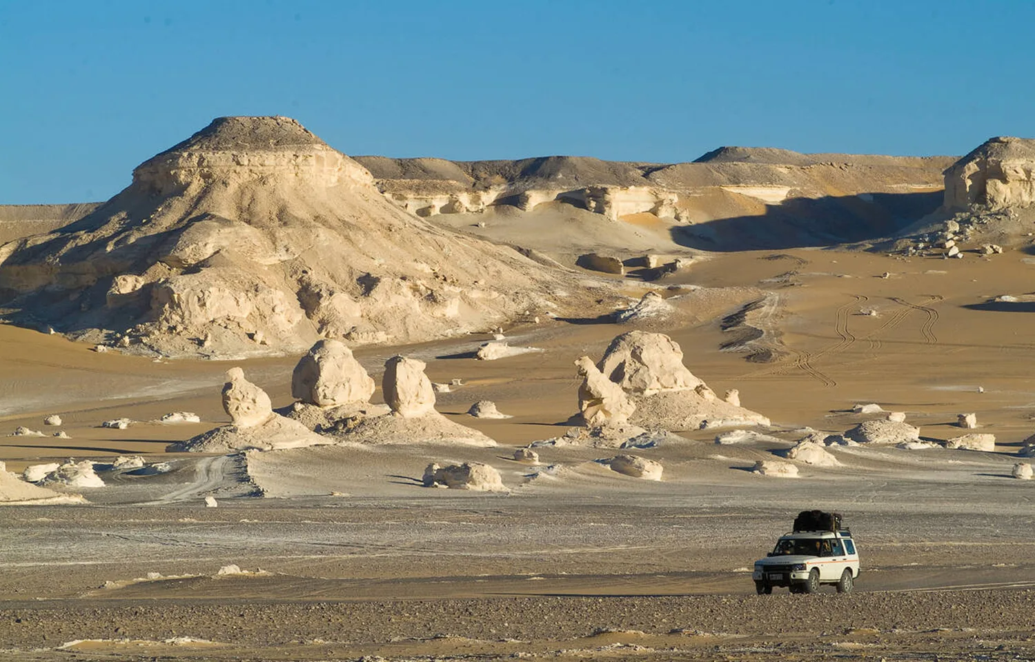 4X4 Vehicle Driving Through The White Desert Landscape In Egypt For A Desert Adventure.