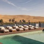 Swimming pool and deck chairs on a Nile cruise ship, with the desert hills and riverbank in the background.