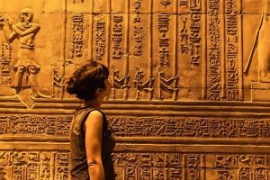 Tourist explores Kom Ombo Temple, a highlight of Egypt Holiday Packages From Toronto. A tourist looking at ancient hieroglyphics on the walls of the Kom Ombo Temple, a highlight of Egypt vacation packages from Toronto.