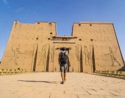 A tourist visiting Edfu Temple on Egypt Packages From Canada. A tourist walking towards the Edfu Temple, a key destination for package tours to Egypt from Canada.