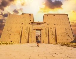 A tourist enters Edfu Temple, a highlight of Egypt Tours From Melbourne. A tourist walking towards the entrance of the Edfu Temple, a key destination in Egypt holiday packages from Melbourne.