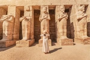 Tourist visits Karnak Temple, a highlight of Egypt Tours From Toronto. A tourist standing in front of large statues at the Karnak Temple, a key sight on Egypt tours from Toronto.