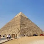 A sunny Egypt layover sightseeing trip featuring the majestic Great Pyramid of Giza with tourists in the foreground