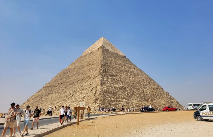 A sunny Egypt layover sightseeing trip featuring the majestic Great Pyramid of Giza with tourists in the foreground