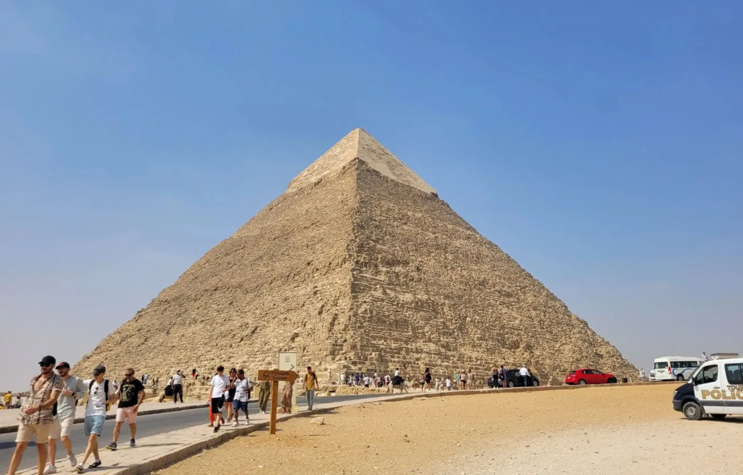 A sunny Egypt layover sightseeing trip featuring the majestic Great Pyramid of Giza with tourists in the foreground