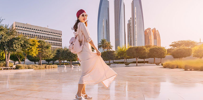 Experience the fusion of modernity and tradition as an Indian woman walks against the backdrop of Abu Dhabi iconic skyscrapers