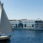 Large white MS Grand Rose cruise ship sailing past a smaller sailboat (felucca) on the Nile.