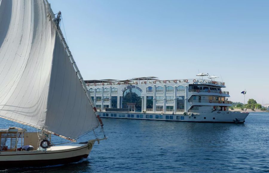 Large white MS Grand Rose cruise ship sailing past a smaller sailboat (felucca) on the Nile.