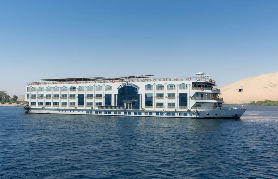 White, multi-deck Nile cruise ship with arched windows sailing in overcast conditions.