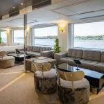Spacious main lounge or bar area on the MS Farah cruise ship with large picture windows offering a panoramic view of the Nile.