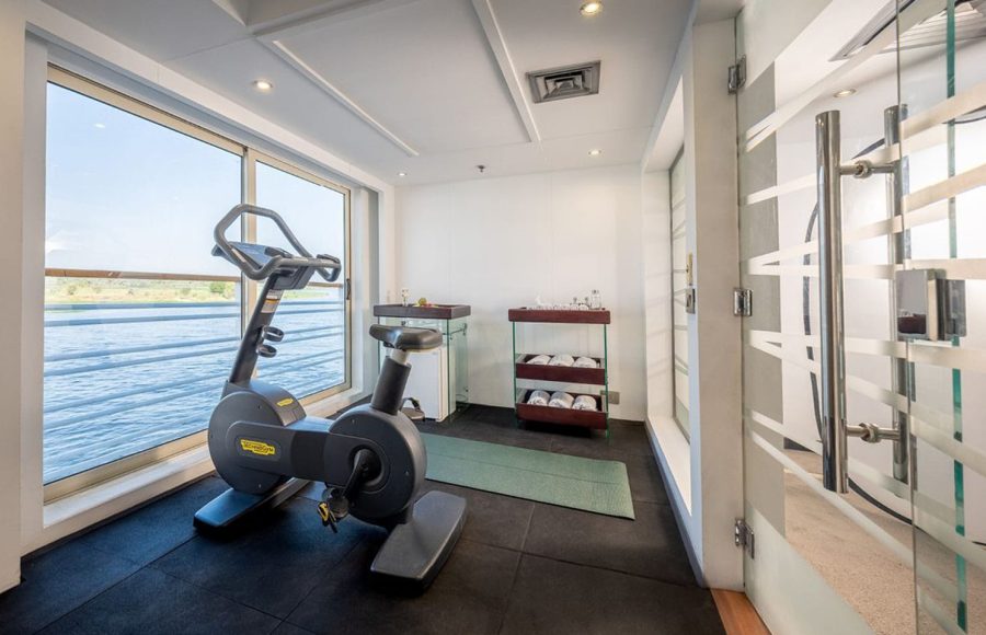 Fitness room on the MS Farah cruise ship with an exercise bike facing a large window overlooking the Nile River.