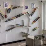 Creative bookshelf installation in the MS Farah library/lounge area, with white sofas and a glass door leading to the deck overlooking the river.