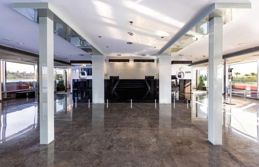 Modern reception and lobby area of the MS Farah cruise ship with glossy black marble flooring, white pillars, and a dark reception desk.