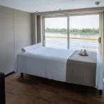 Massage treatment room on the MS Farah cruise ship with a massage bed and sliding glass door with a Nile view.