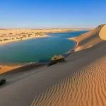 Close-up of patterned sand dunes sloping down to an oasis lake, perfect for a Fayoum day trip from Cairo