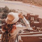 Female-tourist-holding-her-hat-and-admiring-the-landscape-over-Ait-Benhaddou-Ksar-an-ancient-fortified-city-in-Morocco-near-Ouarzazate