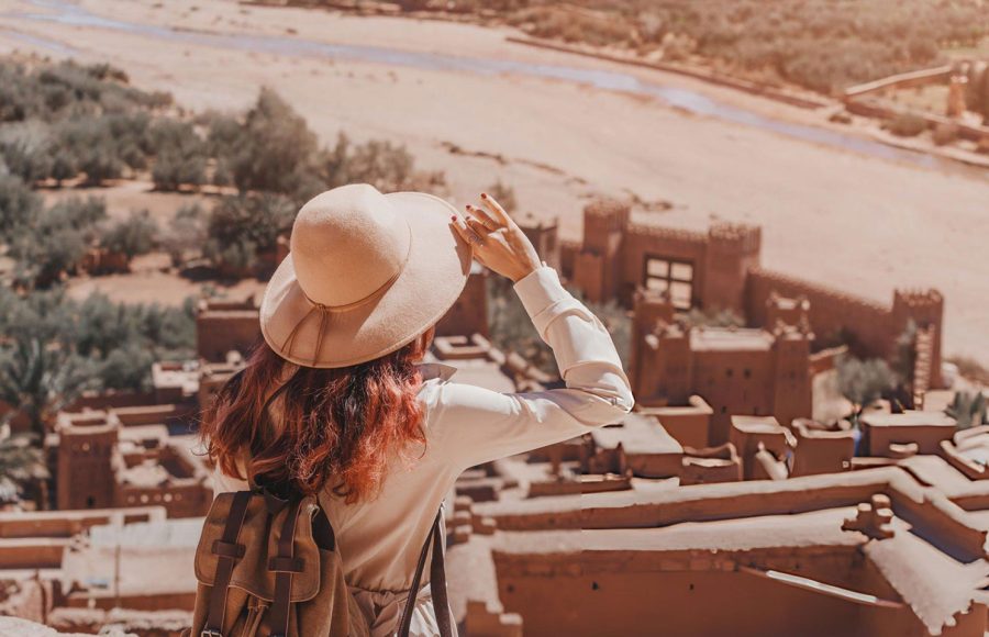 Female-tourist-holding-her-hat-and-admiring-the-landscape-over-Ait-Benhaddou-Ksar-an-ancient-fortified-city-in-Morocco-near-Ouarzazate